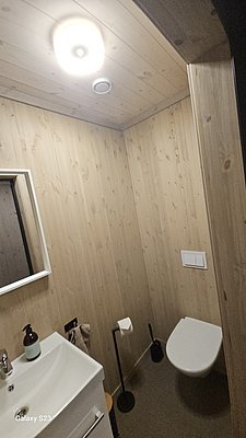 Ein modernes Badezimmer in Hitra, Norwegen, mit Holzverkleidung, Waschbecken und Toilette. Die gemütliche Atmosphäre eignet sich ideal für einen komfortablen Angelurlaub. Perfekt für Entspannung nach einem erfolgreichen Angelausflug.