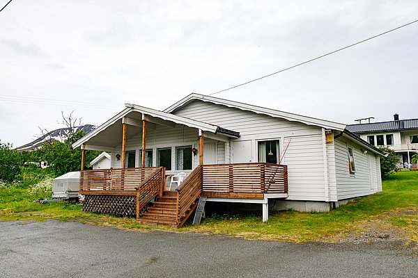 Gemütliches Holzhaus mit überdachter Veranda in Nord-Norwegen. Umgeben von grüner Landschaft und Bergen, idealer Ausgangspunkt für Angelabenteuer und Naturerlebnisse. Perfekt für entspannte Angelferien in skandinavischer Umgebung.