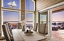 Gemütliches skandinavisches Interieur mit Panoramafenstern und atemberaubendem Blick auf den Fjord in Südwest-Norwegen. Holztisch mit Deko, einladende Atmosphäre – perfekt für einen unvergesslichen Angelurlaub in traumhafter Naturkulisse.