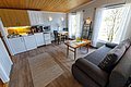 Gemütlicher Wohnbereich in einer norwegischen Hütte auf Hitra, Norwegen. Offene Küche, Esstisch, Sofa und große Fenster mit Ausblick auf die Natur. Perfekt für Angelreisende, die Komfort und Abenteuer vereinen möchten.
