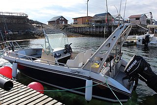 Angelboot im Hafen von Nord-Norwegen, bereit für Meeresangeln. Klare Wasser und malerische Küstenlandschaft im Hintergrund. Perfekter Ausgangspunkt für spannende Angelabenteuer in der atemberaubenden Natur Skandinaviens.