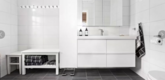 Helles, modernes Badezimmer mit weißer Einrichtung, großen Fliesen und dunklem Boden in Nordland, Norwegen. Elegante Details wie Handtücher und stilvolle Accessoires schaffen eine einladende Atmosphäre für Entspannung und Erfrischung.