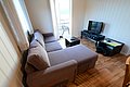Gemütliches Wohnzimmer in Nord-Norwegen mit L-förmigem Sofa, Fernseher und Zugang zu einem Balkon mit beeindruckendem Ausblick. Perfekt für erholsame Angelreisen.
