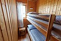 Kleines Schlafzimmer aus Holz mit einem Etagenbett und einem Fenster mit Vorhang in Hitra, Norwegen. Gemütliche Unterkunftsidee für Angelreisen. Ideal für Erholung nach einem erlebnisreichen Angeltag.