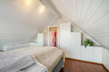 Gemütliches Schlafzimmer in Südwest-Norwegen mit Holzverkleidung, weißem Schrank und Pflanzen. Ideal für Erholung bei Angelurlauben. Skandinavischer Charme lädt zum Entspannen nach einem erfolgreichen Angeltag ein. Perfekte Unterkunft für Naturverbundene.