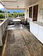 Überdachte Terrasse in Hitra, Norwegen, mit Holzboden, Tisch und Stühlen, ideal für Angelpausen. Die Umgebung bietet grünes Panorama und entspannten Rückzugsort. Perfekt für Deinen Angelurlaub in bezaubernder Naturkulisse.