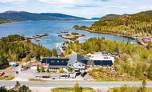 Luftaufnahme der malerischen Küstenlandschaft von Hitra, Norwegen: grüne Wälder, idyllische Inseln und das Meer versprechen ein fantastisches Angelabenteuer. Ideal für Erholungssuchende und Angler, die die Natur genießen möchten.