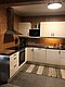 Gemütliche Küche in Hitra, Norwegen. Moderne Ausstattung mit Holzverkleidung, weißem Küchenschrank, Spüle und Herd auf Holzboden. Ideal für Angelurlaub. Entspannt kochen nach ereignisreichem Angelausflug in der idyllischen Umgebung.