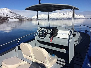 Aluminiumboot auf ruhigem Wasser in Nord-Norwegen, umgeben von schneebedeckten Bergen. Perfekt für Angelreisen und unvergessliche Abenteuer in einzigartiger Landschaft. Ideal für Meeresangeln und Naturerlebnisse.