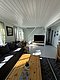 Gemütliches Ferienhaus in Hitra, Norwegen: Helle Holzverkleidung, große Fenster, komfortable Couch und Esstisch laden zum Entspannen nach einem erfolgreichen Angeltag ein. Perfekt für erholsame Angelurlaube in beeindruckender Naturkulisse.