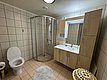 Modernes Badezimmer in Norwegen mit gefliesten Wänden, runder Duschkabine, Holzmöbeln und Waschbecken. Perfekt für Erholung nach dem Angeln in Hitra & Umgebung. Ideal für Angelreisen mit Komfort.