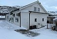 Schneebedecktes weißes Haus in Nord-Norwegen vor Bergen und einem Fluss. Ideal für Angelreisen, umgeben von winterlicher Natur und atemberaubender Landschaft. Perfekter Ausgangspunkt für Erkundungen und Angelabenteuer im hohen Norden.