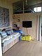 Gemütlicher Innenraum in Nordland, Norwegen: Holzwände, Sofa mit Kissen, Teppich, TV an der Wand. Ein Hochbett bietet zusätzlichen Schlafplatz. Perfekt für Naturliebhaber und Angler auf der Suche nach Komfort und Entspannung.