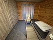 Gemütliches Schlafzimmer in einer Holzhütte auf Hitra, Norwegen. Zwei Einzelbetten, gestreifte Vorhänge und warme Beleuchtung schaffen eine einladende Atmosphäre. Ideal für Angelurlauber und Naturliebhaber, die Entspannung und Abenteuer suchen.