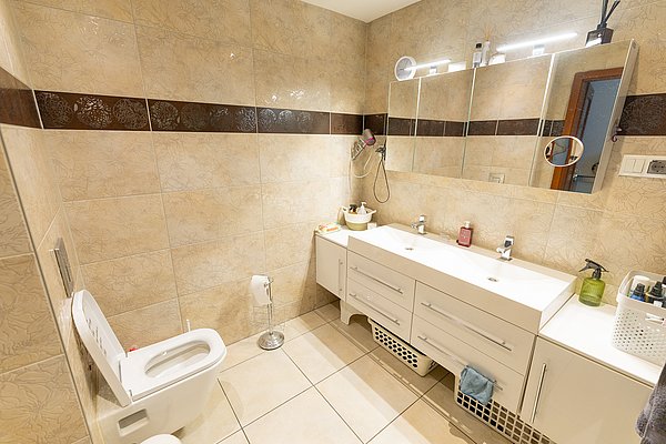 Helles, modernes Badezimmer in Nord-Norwegen mit Doppelwaschbecken, Fliesenwänden und dekorativen Mustern. Perfekt für Entspannung nach einem aufregenden Angeltag. Ideal für Angelurlaub in komfortabler Unterkunft.