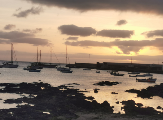 Sonnenuntergang in São Vicente, Kapverden: Bootsanleger mit Segelbooten im ruhigen Wasser, unter einem Himmel voller Wolken. Ideal für Angelreisen, die Abenteuer und Entspannung am Meer kombinieren.