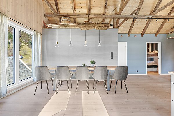 Modernes Interieur in Südwest-Norwegen: Helle Holzbalkendecke, stilvolle Pendelleuchten, langer Esstisch mit grauen Stühlen, große Fenster mit Blick auf Landschaft. Perfekt für naturnahen Angelurlaub und skandinavische Gemütlichkeit.