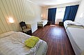 Gemütliches Schlafzimmer in Hitra, Norwegen, mit vier Einzelbetten, Holzboden, sanfter Beleuchtung und blauen Vorhängen. Ideal für Angelurlauber, die Erholung und Komfort nach einem erfolgreichen Angeltag suchen.