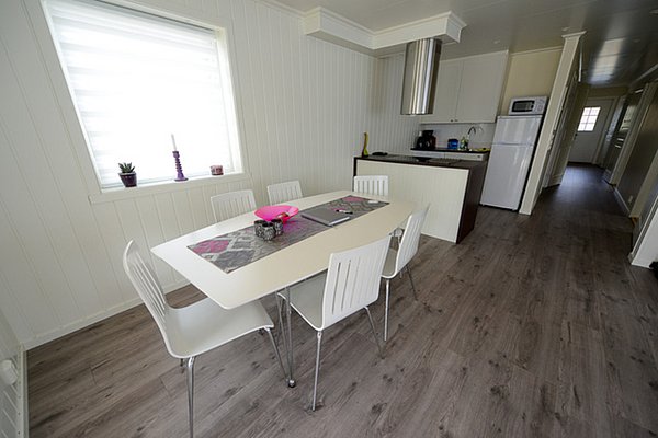 Gemütliche skandinavische Küche in Nordland, Norwegen, mit hellen Wänden, modernem Esstisch, Stühlen und komplett ausgestatteter Kochnische. Ideal für Angelurlaub und entspannte Abende nach erfolgreichen Angelausflügen.