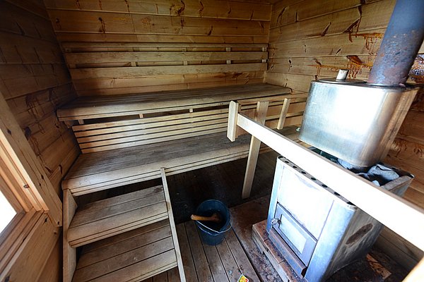 Traditionelle Holzhütte-Sauna in Nord-Norwegen mit Holzofen und Holzbänken. Idealer Ort zur Entspannung nach einem erfolgreichen Angelausflug. Perfekt für einen erholsamen Angelurlaub.