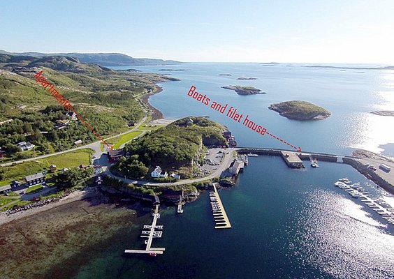 Luftaufnahme von Hitra, Norwegen: malerische Küste mit Anlegeplätzen, Apartments und Filetierhaus. Ideal für Angelurlaub, gefüllte Boote und atemberaubende Landschaften. Perfekter Ausgangspunkt für Meeresangeln und Erholung.