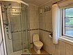 Helles, modernes Badezimmer in Hitra, Norwegen. Ausgestattet mit Dusche, Toilette und Fenster mit Blick auf grüne Landschaft. Ideal für Angelurlauber, die Komfort und Natur genießen möchten.