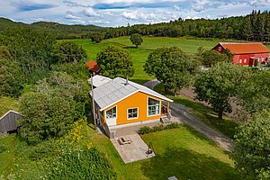 Helles gelbes Haus in grüner, malerischer Landschaft von Hitra, Norwegen. Umgeben von Wiesen und Bäumen, ideal für Angelreisen und erholsame Naturerlebnisse. Perfekte Kulisse für Abenteuer und Entspannung.