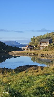 Skandinavische Idylle auf Hitra: Ruhiger Fjord spiegelt grünes Ufer, modernes Ferienhaus inmitten unberührter Natur. Perfektes Angelziel für Abenteurer und Naturliebhaber in Norwegen. Ideal für Angelreisende!