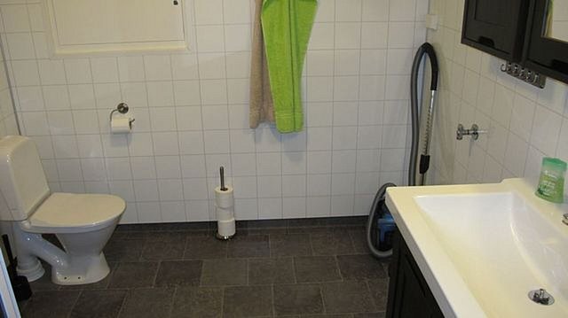 Helles, funktionales Badezimmer in Hitra, Norwegen: Weiße Fliesen, modernes Waschbecken, Toilette, Handtuchhalter. Praktisch für Angelreisende, die Komfort und Sauberkeit suchen. Ideal für entspanntes Erholen nach einem erfolgreichen Angeltag.