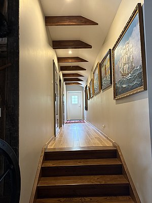 Ein Flur in Nord-Norwegen mit Holzwänden, Gemälden und Teppich. Die gemütliche Einrichtung lädt zum Entdecken ein. Ideal für kulturelle Erlebnisse und nordische Atmosphäre.