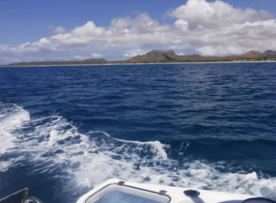 Blaues Meer vor São Vicente, Kapverden: Wellen brechen am Boot, im Hintergrund majestätische Berge und dramatischer Himmel. Perfektes Reiseziel für Angelabenteuer und Naturerlebnisse im Atlantik.