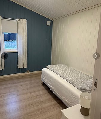 Gemütliches Schlafzimmer in Hitra, Norwegen. Einzelbett, helle Holzwände und blauer Akzent. Ideal für Angelurlaube in der Region Hitra & Umgebung. Ruhige, einladende Atmosphäre mit Tageslicht durch Fenster.