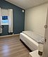Gemütliches Schlafzimmer in Hitra, Norwegen. Einzelbett, helle Holzwände und blauer Akzent. Ideal für Angelurlaube in der Region Hitra & Umgebung. Ruhige, einladende Atmosphäre mit Tageslicht durch Fenster.