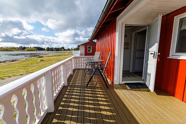 Die rote Holzhütte mit offener Veranda bietet direkten Meerblick und Naturerlebnis in Hitra, Norwegen. Perfekt für Angelurlaub, entspanntes Meeresangeln und idyllische Tage an der Küste. Ideal für Outdoor-Abenteuer und Entspannung.