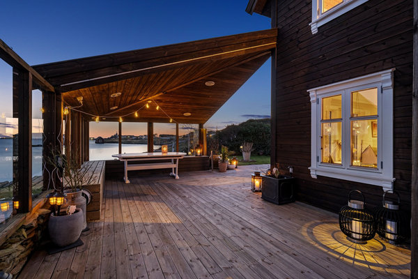 Gemütliche Terrasse in Südwest-Norwegen mit Holzverkleidung und stimmungsvoller Beleuchtung bei Dämmerung. Perfekter Ort für entspannte Angelabende, umgeben von malerischer Fjordlandschaft und ruhiger Atmosphäre. Ideal für Angelurlaub und Naturgenuss.