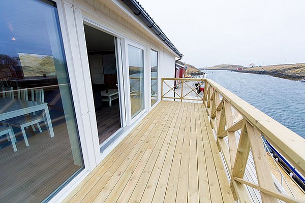 Modernes Ferienhaus in Nordland, Norwegen: Holzveranda mit Blick auf ruhigen Fjord. Perfekte Unterkunft für Angelurlauber und Naturliebhaber. Entspanne in atemberaubender Umgebung und genieße die skandinavische Ruhe. Ideal für Meeresangeln und Abenteuer.