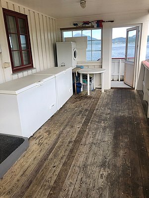 Anglerhütte auf Hitra, Norwegen: Geräumige Terrasse mit Gefrierschrank, Waschmaschine und beeindruckendem Fjordblick. Perfekt für einen Angelurlaub in malerischer Umgebung, ideal zur Verarbeitung und Lagerung des Fangs.