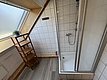 Modernes Badezimmer auf Hitra, Norwegen: Duschkabine, helle Fliesen, Holzregal mit Pflanze und Dachfenster. Komfortable Unterkunft für Angelreisende, ideal für entspannte Stunden nach erfolgreichen Angelausflügen. Perfekt für einen erholsamen Angelurlaub.