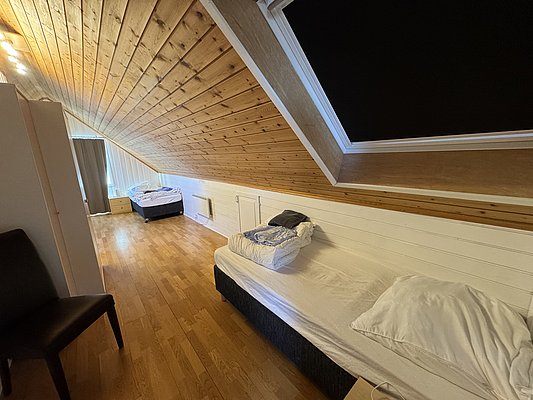 Gemütliches Schlafzimmer in Hitra, Norwegen, mit Holzdecken, zwei Betten und hellem Holzfußboden. Ideal für erholsame Angelurlaube. Hell und einladend gestaltet, mit Dachfenster für natürlichen Lichteinfall. Perfekte Unterkunft für Fischabenteuer.