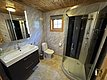 Modernes Badezimmer auf Hitra, Norwegen: Holzdecke, helles Waschbecken mit Spiegel, Duschkabine und Fenster für Tageslicht. Ideal für komfortablen Angelurlaub.