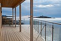 Moderne Terrasse mit Glasgeländer in Hitra, Norwegen, bietet weiten Blick aufs Meer und eine kleine Insel. Ideal für Angelreisen und Naturerlebnisse in skandinavischer Ruhe. Perfekter Ausgangspunkt für Meeresangeln und Erholung.