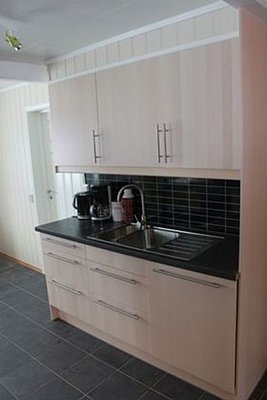 Helles, modernes Küchendesign in Nord-Norwegen mit schwarzen Fliesen, hellem Holz, Spüle und Kaffeemaschine. Ideal für Angelreisende zur Selbstverpflegung. Funktionale, gemütliche Ausstattung für einen komfortablen Aufenthalt.