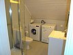 Helles, modernes Badezimmer mit Dusche, Waschmaschine, Trockner und Waschbecken in Nordland, Norwegen. Ideal für komfortable Angelreisen, bietet es funktionale Annehmlichkeiten direkt im Ferienhaus. Perfekt für längere Aufenthalte in der Natur.