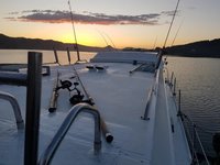 Das Bild zeigt ein Boot bei Sonnenuntergang mit mehreren Angelruten an Deck, während es auf einem ruhigen Gewässer liegt.