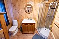 Holzverkleidetes Badezimmer in Nordland, Norwegen, mit runder Dusche, Waschbecken und Toilette. Rustikaler Charme und warme Atmosphäre für erholsamen Angelurlaub. Ideal für Komfort suchende Angler.