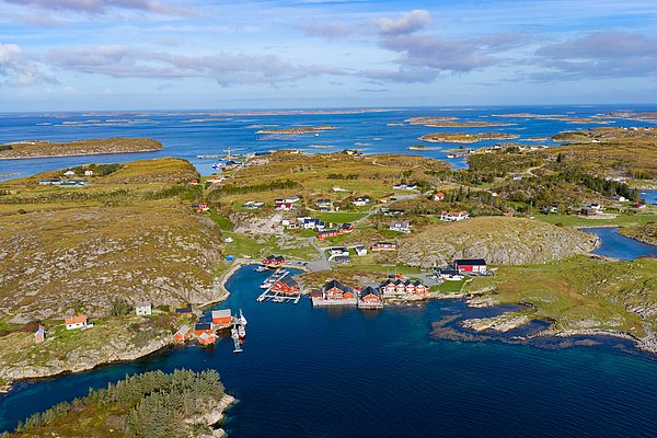 Luftaufnahme von Hitra, Norwegen: Malerische Inseln und Küstenlandschaft, bunte Häuser am Wasser, ideal für Angelurlaube. Klare blaue See und weitläufige grüne Hügel in natürlicher Schönheit, perfekt für Erholung und Abenteuer.