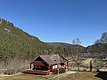 Rotes Holzhaus in malerischer Landschaft von Hitra, Norwegen. Umgeben von dichten Wäldern, Bergen und klarem Himmel. Ideal für Angelurlaube und Naturgenuss in skandinavischer Idylle. Perfekter Ausgangspunkt für Abenteurer und Erholungssuchende.