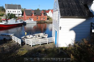 Idyllische Küstenlandschaft in Südwest-Norwegen mit traditionellen Holzhäusern am Wasser, Fischerbooten und einem ruhigen Hafen. Perfekt für Angelurlaub und entspannende Auszeiten in malerischer Natur.