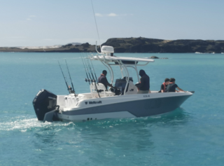 Boot mit Anglern im klaren, türkisblauen Wasser vor der Küste Nord-Norwegens. Perfektes Setting für Angelurlaub und Meeresangeln. Ideal für Abenteuer und ertragreiche Fänge in atemberaubender, skandinavischer Natur.