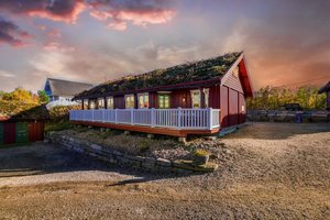 Idyllisches rotes Ferienhaus mit Grasdach in der Region Hitra, Norwegen. Perfekte Unterkunft für Angelreisen, umgeben von malerischer Natur und atemberaubendem Sonnenuntergang. Ideal für Erholung und Abenteuer.